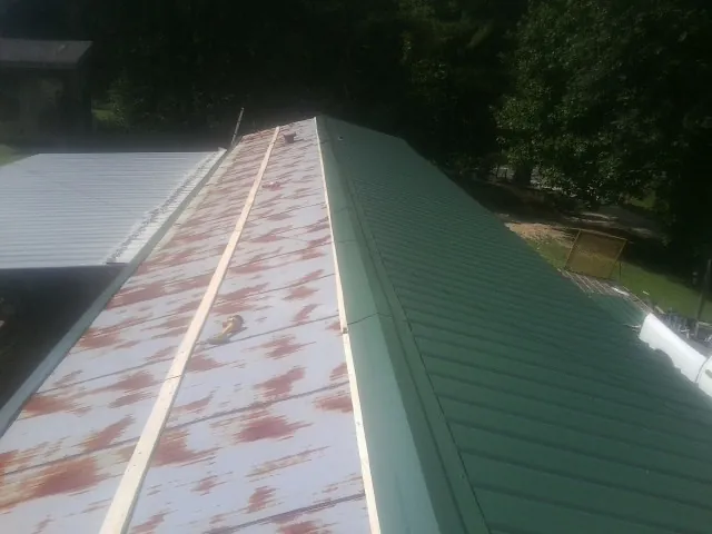 Old rusted panels beside newly installed green metal roofing — Wind Damage Roof Repair by Roofing Brothers in Aledo