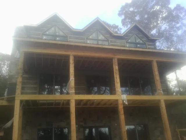 Dormers and porch framing on a large log home under construction — Roof Coating work by our crew in Aledo