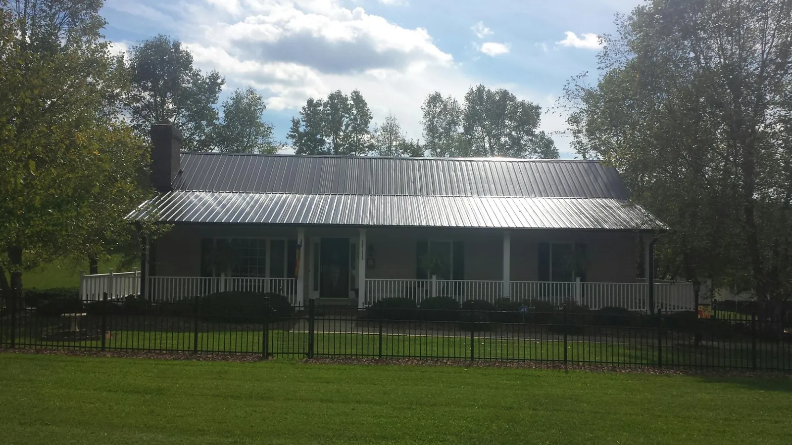 Gray metal roof on a brick ranch with a full width front porch — Gutter Guard Installation work by our crew in Aledo