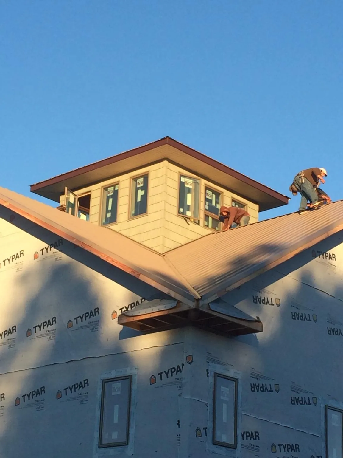 Roofers working around a rooftop cupola on a new metal roof at sunset — Roof Waterproofing in Aledo by Roofing Brothers